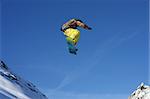 Young snowboarder jumping high over the mountains