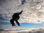 Snowboarder launching off a jump; horizontal orientation, daylight.