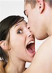 A young man kissing a woman while she makes a surprised/pleased face.