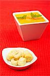 Bread croutons and carrots puree and parsley on red mat. Shallow DOF