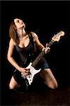 Teenager girl playing electric guitar in dark