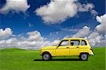 Yellow classic car in a green meadow