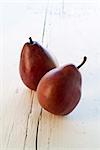 Two Red Pears on white wooden surface