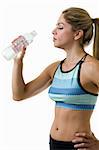 Attractive blond woman in great physical shape wearing workout top about to drink from a bottle of water