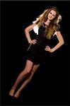 Full body of a beautiful woman with long blond hair standing on black with hair lit wearing a black mini dress