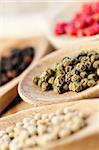 Assorted peppercorns in wooden cooking spoons macro