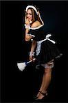 Full body of a beautiful woman with brown hair wearing a French Maid outfit and holding a white feather duster standing on black with hand over mouth