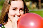 Young woman inflating red balloon