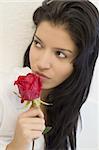 Studio portrait of a stunningly beautiful hispanic girl smelling a red rose