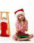 cute little eight year old girl sitting on floor with christmas presents holding a little stuffed dog
