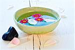 pink flowers and white rose petals floating in a green bowl