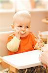 Little baby boy playing with spoon after lunch