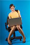 an office worker sitting down with the laptop on her legs and yellow shirt