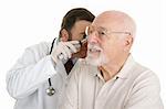 Senior man having his ears checked at the doctors office.  Isolated on white.