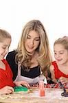 beautiful mother and twin daughters decorating cookies