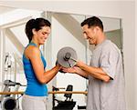 Man and woman lifting weights in gym.