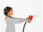 Portrait of pretty young woman holding gas pump nozzle like a gun on white background.