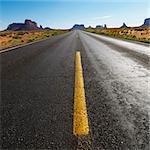 Open road in scenic desert landscape with distant mountains and mesas.