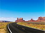 Scenic road in desert landscape with mesa and mountains.