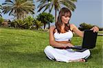 Young beautiful woman on grass is using laptop