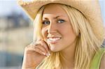 Portrait of a stunningly beautiful young blond woman wearing a straw cowboy hat and bathed in sunshine