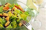 Caesar salad served in a glass bowl and white wine