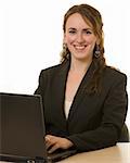 Attractive young brunette woman in business suit sitting at a desk in front of a laptop computer