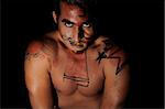 Portrait of latin young male with intense look and bodypaint drawing