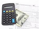 calculator and dollar bills over 1040 tax form