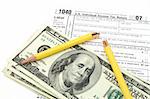 broken yellow pencil over dollars and 1040 tax form