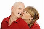 Middle aged couple isolated on white.  Wife is kissing husband on the cheek.