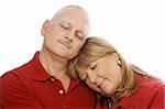 Mature loving couple cuddling with their eyes closed.  White background.