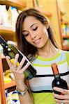 woman in a supermarket comparing two wines