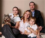 Mum, daddy, two children and yorkshire terrier on a sofa
