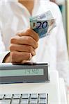 man at the supermarket standing near the cash box and holding 20 Euro