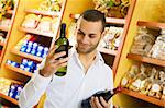 man in a supermarket comparing two wines