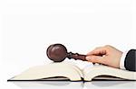 Judge holding a wooden gavel over the law book, reflected on white background