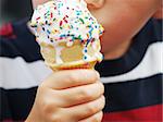a young child's hand holding a dripping ice cream cone with colorful sprinkles