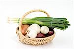 Different sorts of onions in a basket on bright background