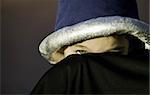 Young boy peeks out from underneath a costume sorcerer hat