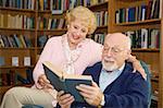 Senior couple enjoying a good book together in the library.