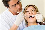 young woman doing dental checkup. Dentist is using an angled mirror