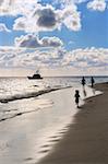 Family taking a walk on a sandy beach of tropical resort at sunset