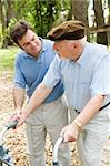 Adult son caring for his aging father who is confined to a walker.