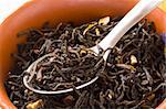 Dry green tea with slices of orange-peels and a bergamot in a clay bowl with spoon close up