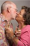 Happy Senior Couple Kissing while holding Champagne glasses.