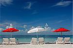 Red and white parasols on a tropical beach with nice blue sky