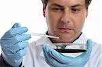 A medical or agricultural scientis, chemist or researcher holding a petri dish and pipet with clear fluid.  Focus to dish and hands