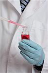 Scientist, chemist, pharmacist or laboratory technician adding a pipetted sample to a laboratory bottle. Focus to hand, pipet and bottle