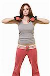 Attractive auburn hair or brunette woman in pink and grey workout attire holding 2 hand weights with serious expression over white